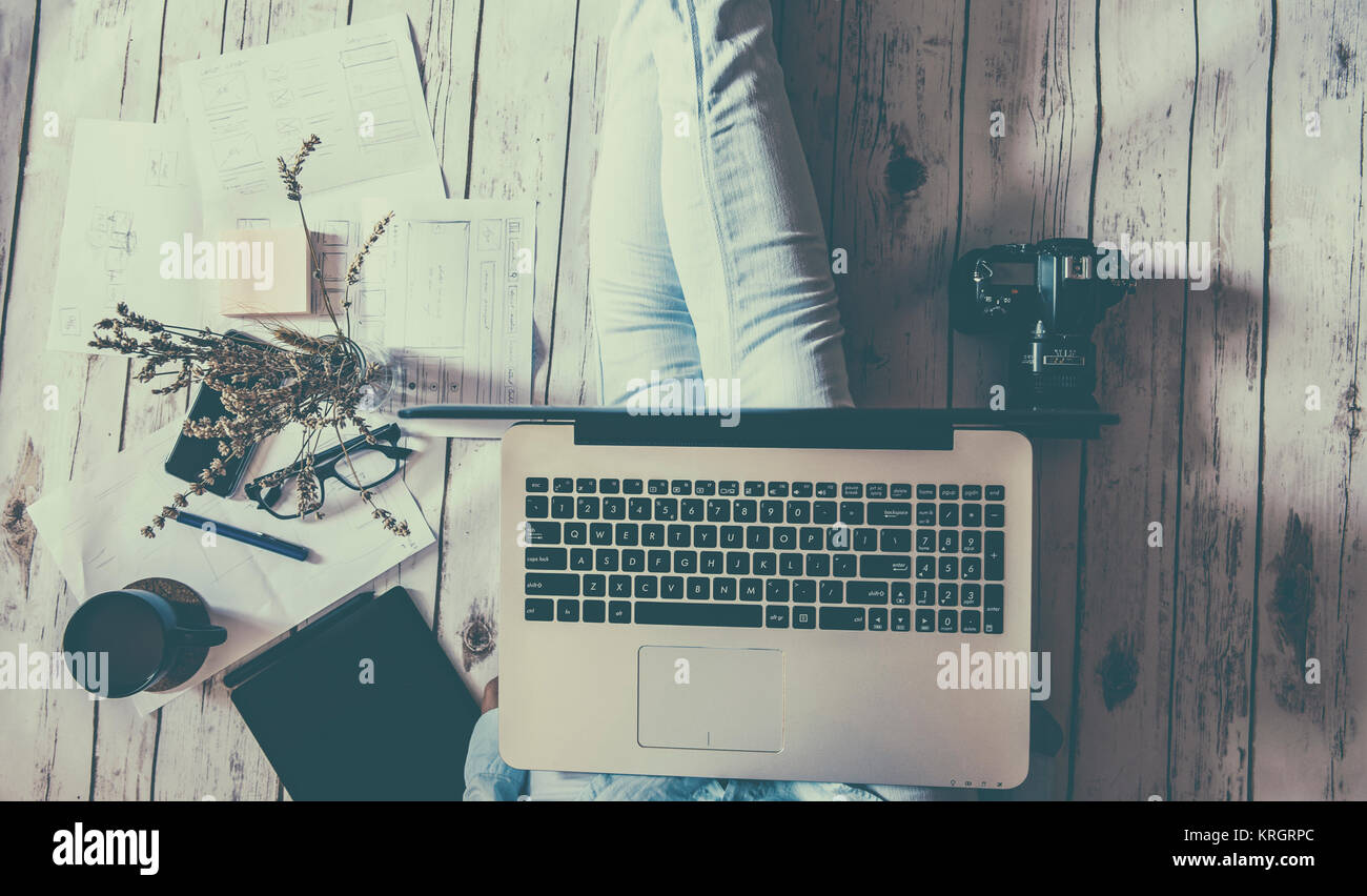 Il lavoro di relax a casa: concetto con una ragazza seduta sul pavimento con laptopand altri strumenti Foto Stock