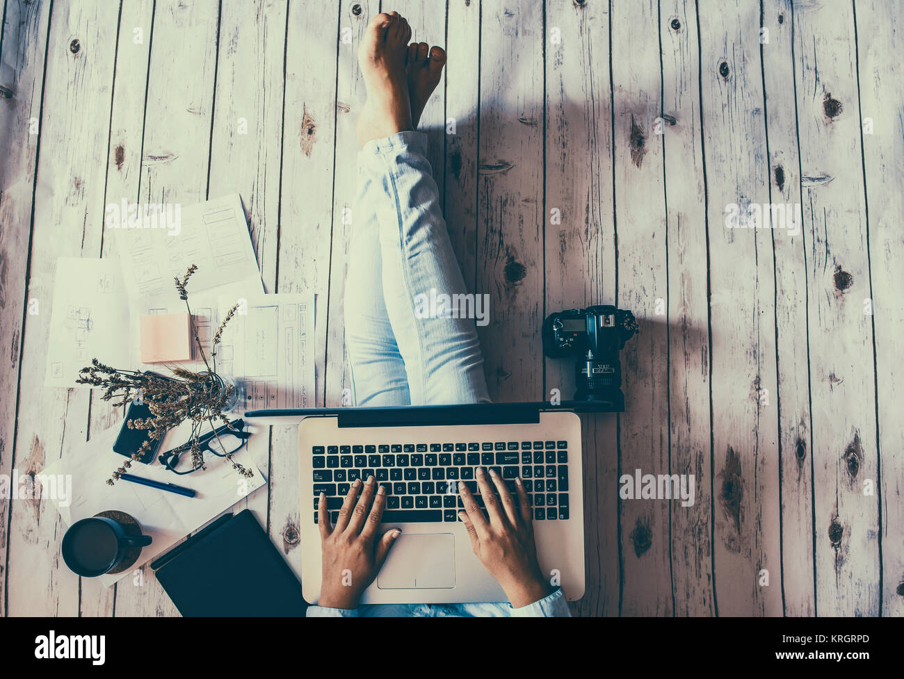 Il lavoro di relax a casa: concetto con una ragazza seduta sul pavimento con laptopand altri strumenti Foto Stock