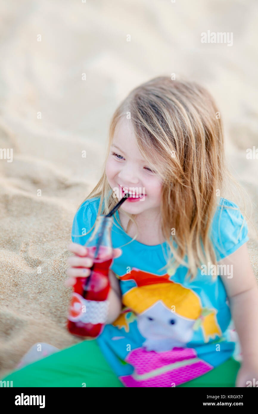 Felice la ragazza della spiaggia di bere succo di frutta Foto Stock