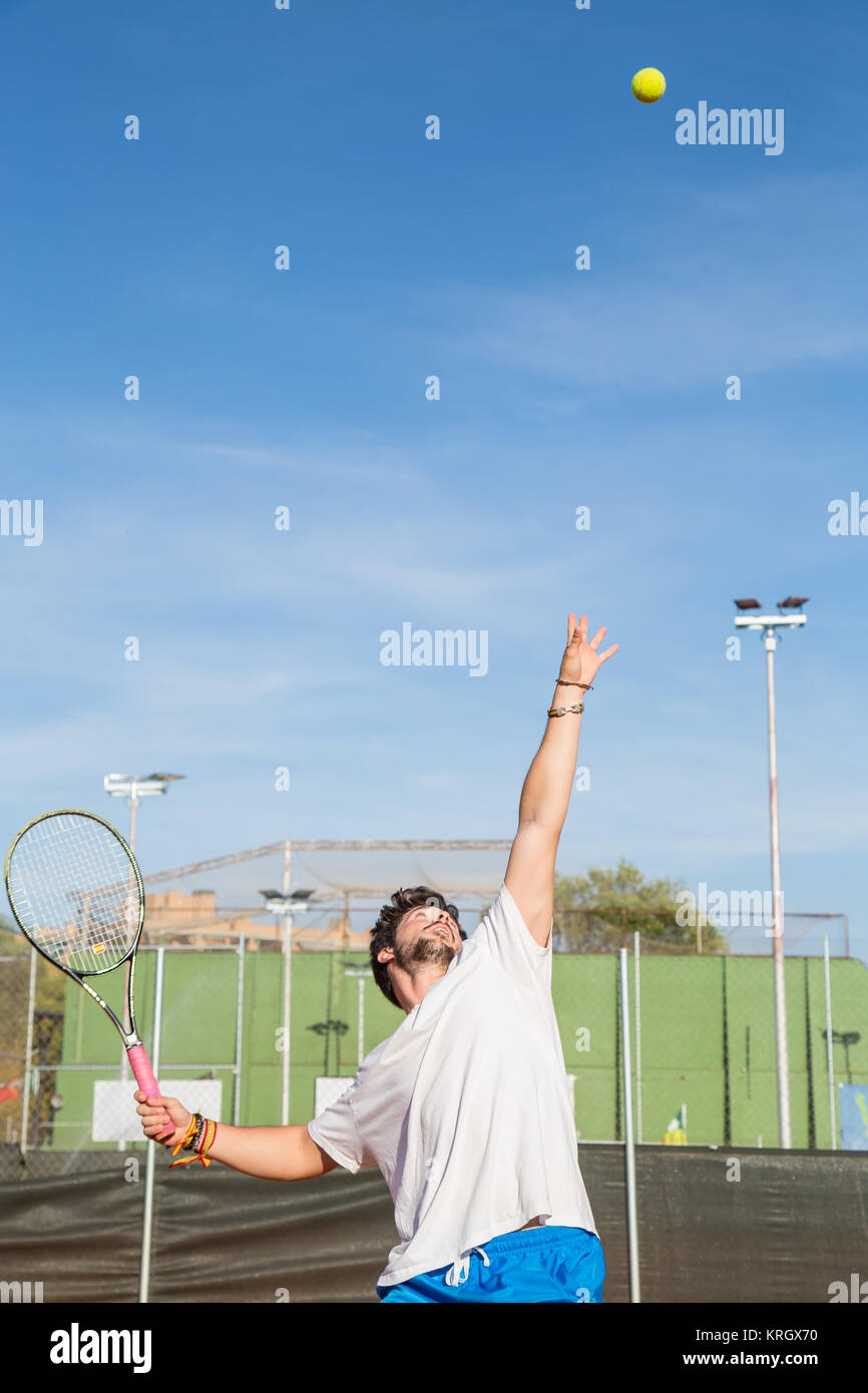 Giocatore di tennis professionista gettando palla in aria prima di urtare contro di essa. Foto Stock