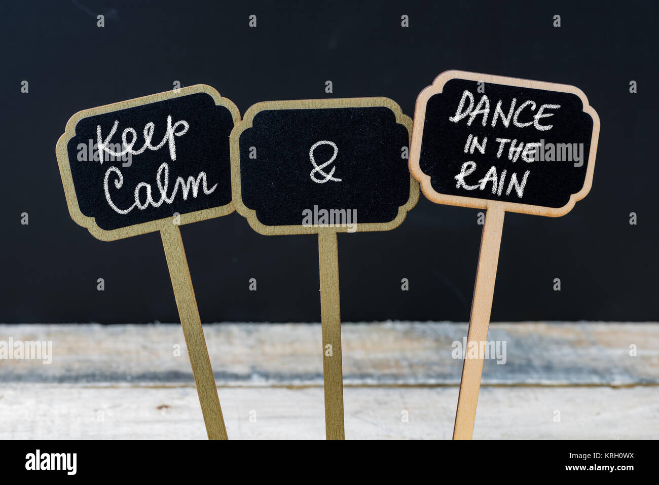 Mantenere la calma e la danza sotto la pioggia messaggio scritto con un gessetto su mini etichette di Blackboard Foto Stock
