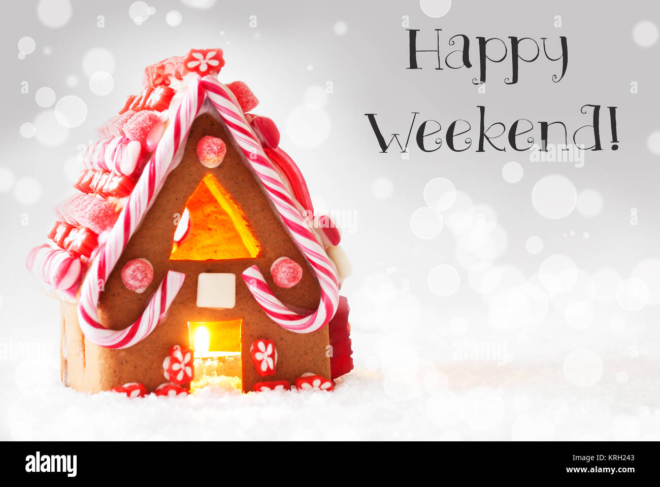 Gingerbread House di scenario innevato come decorazione di Natale. Lume di candela per atmosfera romantica. Argento con sfondo bokeh effetto. Testo inglese Happy Weekend Foto Stock