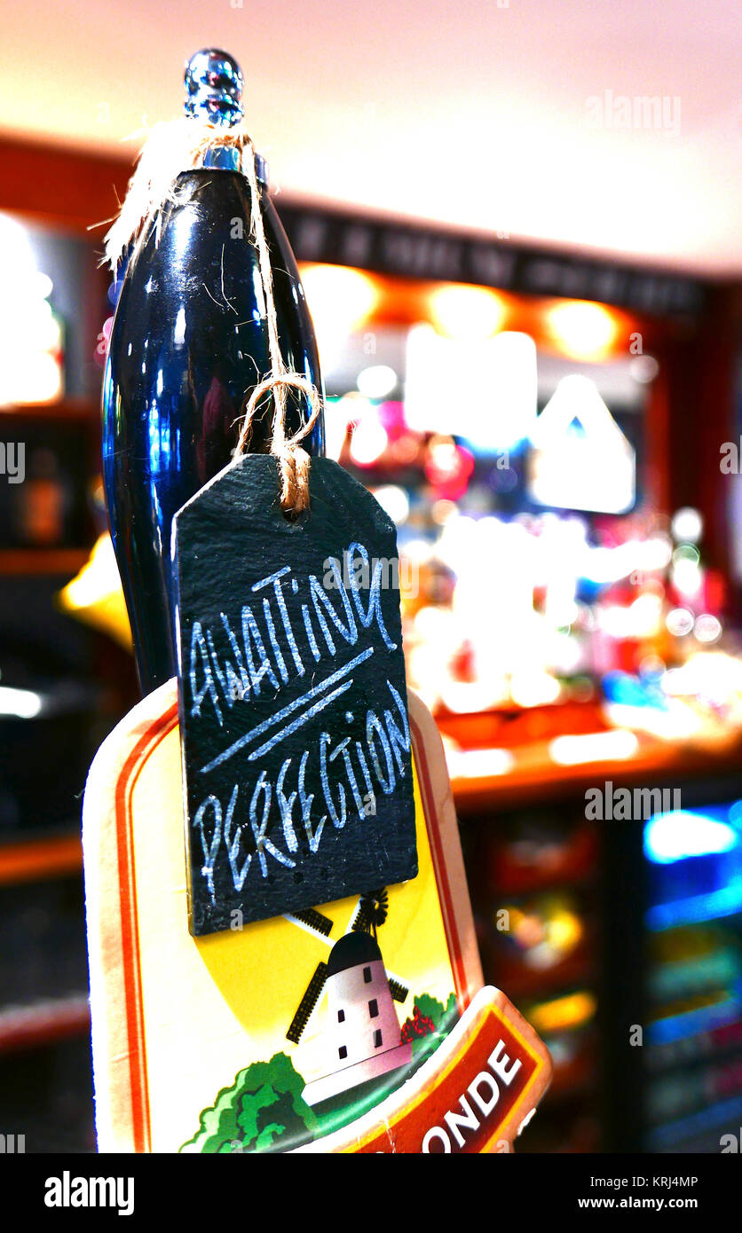 In attesa di perfezione scritto a mano in gesso su lavagna appesi da maniglia di pompa sulla botte di birra in pub Foto Stock