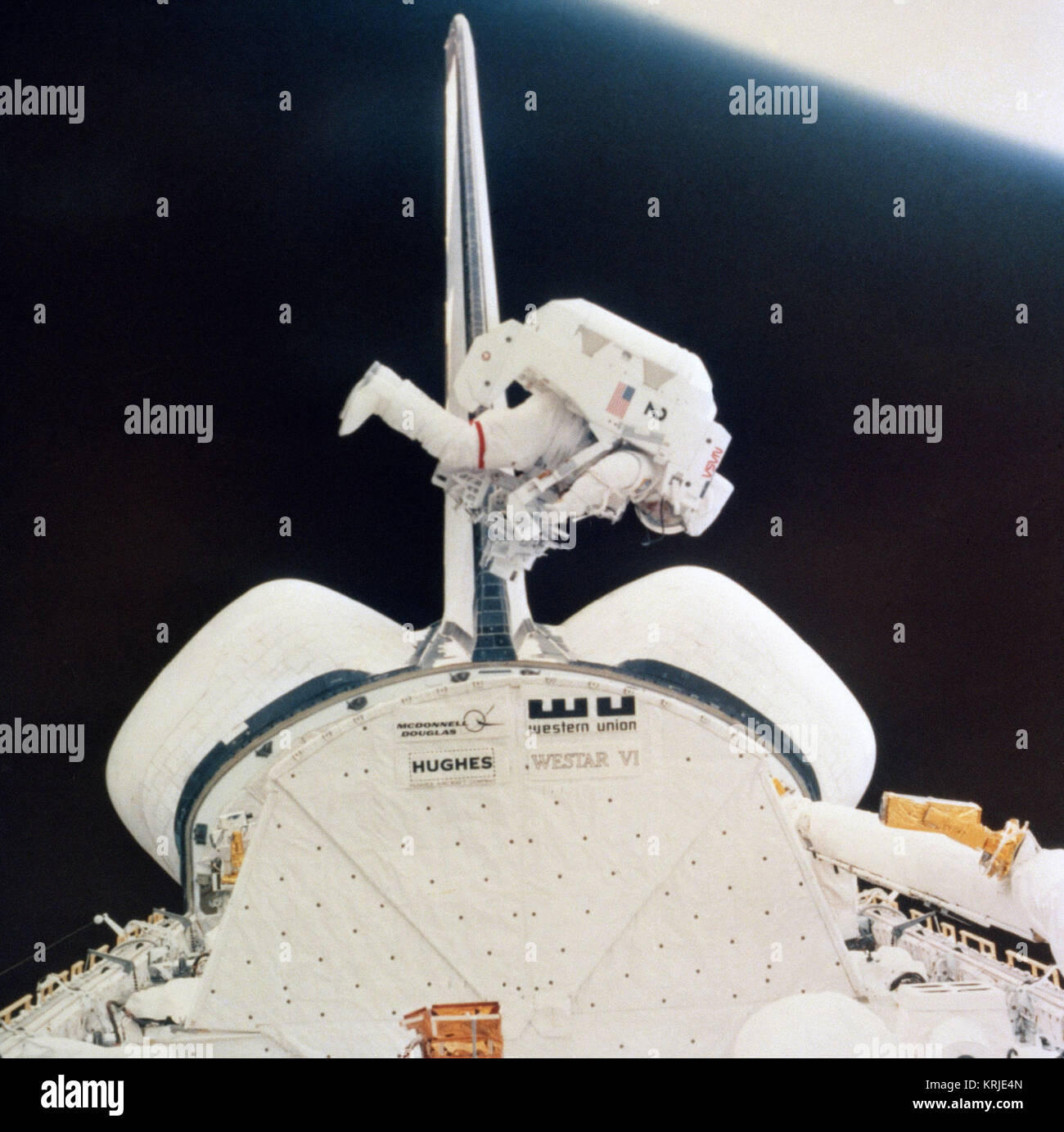 Un astronauta galleggianti libero al di sopra del suo space shuttle come egli compie esperimenti durante una missione spaziale. La Terra è visibile nell'angolo superiore destro. STS-41-B EVA Foto Stock