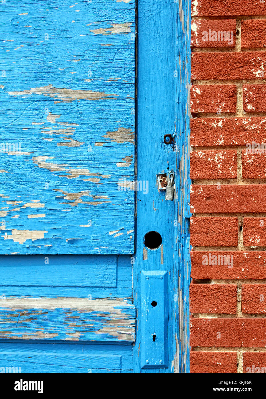 Parte di un peeling blu porta in legno con maniglia mancante è in contrasto contro un rosso un muro di mattoni sul percorso 66 in Stroud, Oklahoma. Foto Stock