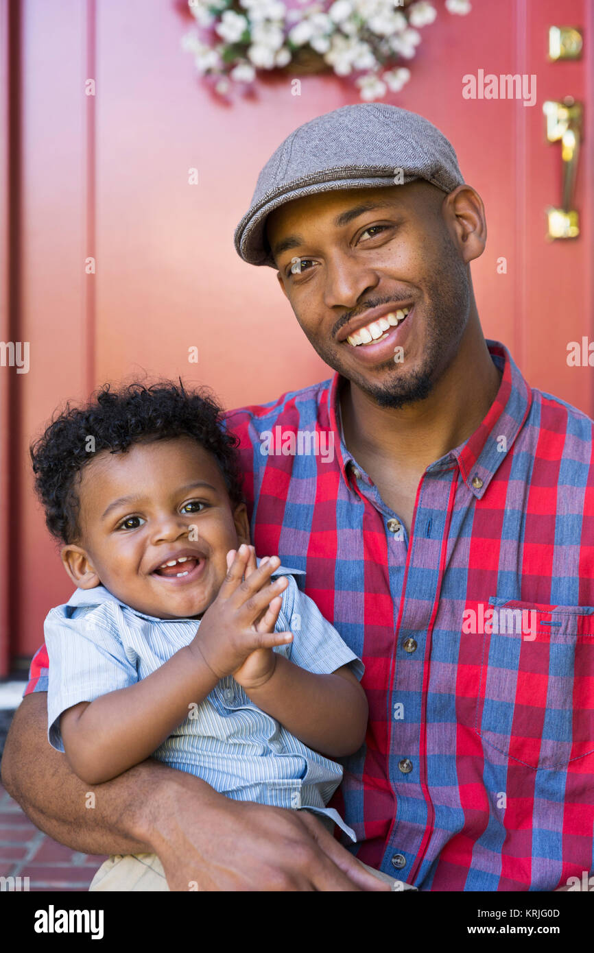 Sorridente razza mista padre e figlio bambino seduto sulla parte anteriore stoop Foto Stock
