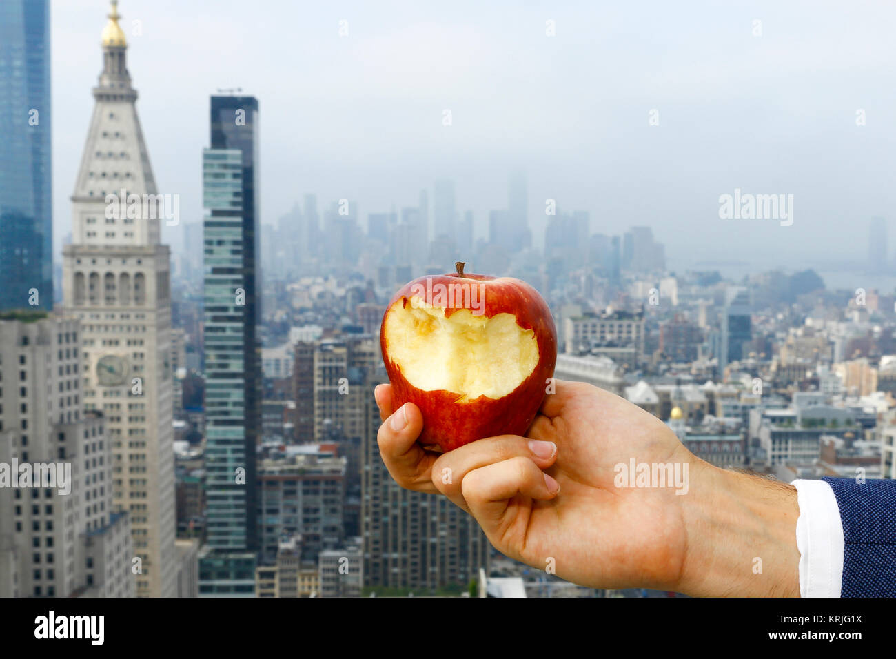 Mano di uomo caucasico holding morso apple sul tetto urbano Foto Stock