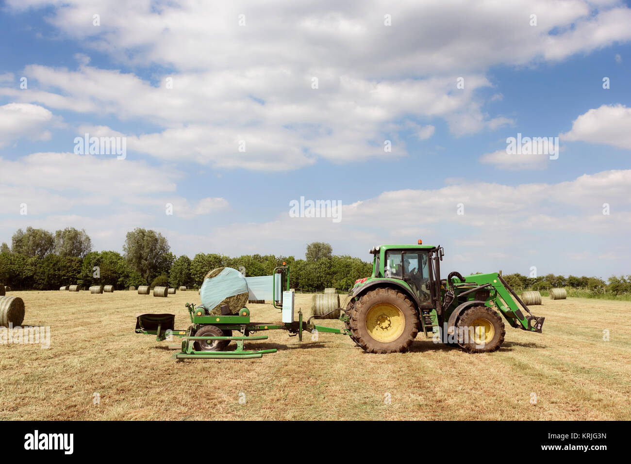 Uomo caucasico guidando il trattore pressatura di fieno Foto Stock