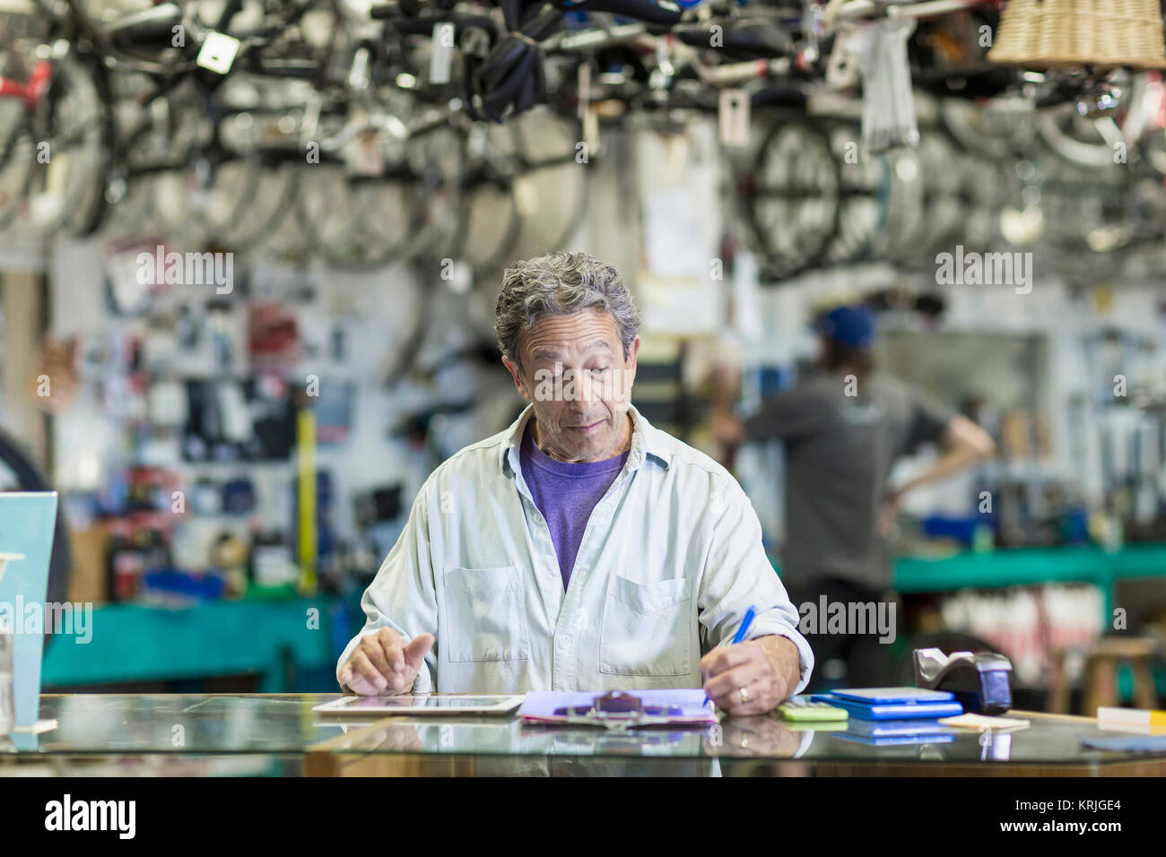 Uomo caucasico nel negozio di biciclette iscritto negli appunti Foto Stock