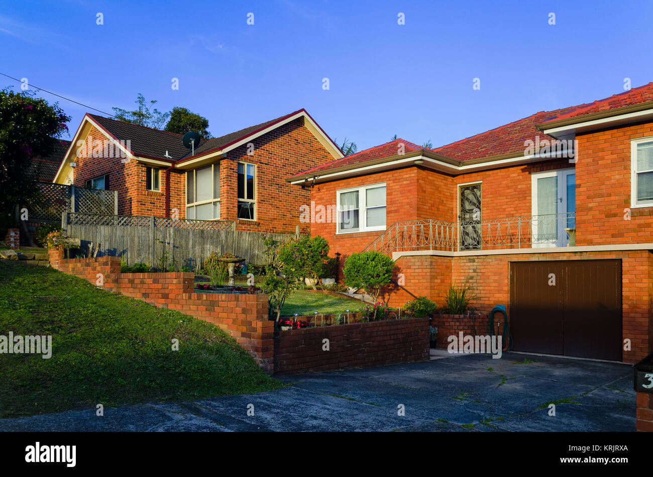Suburban casa in mattoni rossi Esterni al tramonto di Sydney in Australia. La costruzione di prati e strade private su una strada suburbana in Brookvale, Sydney, Australia. Foto Stock
