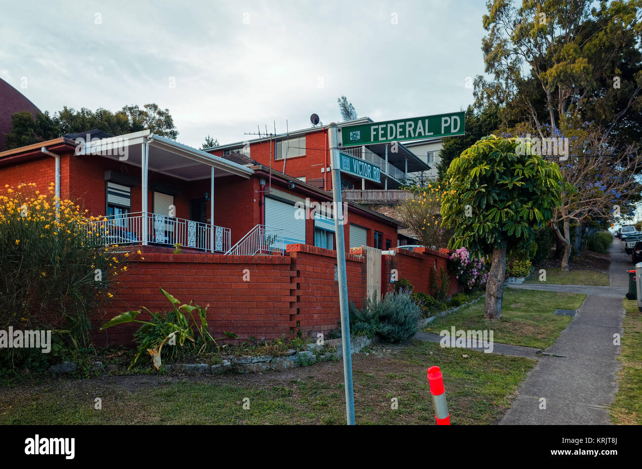 Un tipico quartiere periferico di Australia sentiero o il marciapiede con edifici residenziali, erba e alberi. Sobborgo di Brookvale in spiagge settentrionali area di Sydne Foto Stock