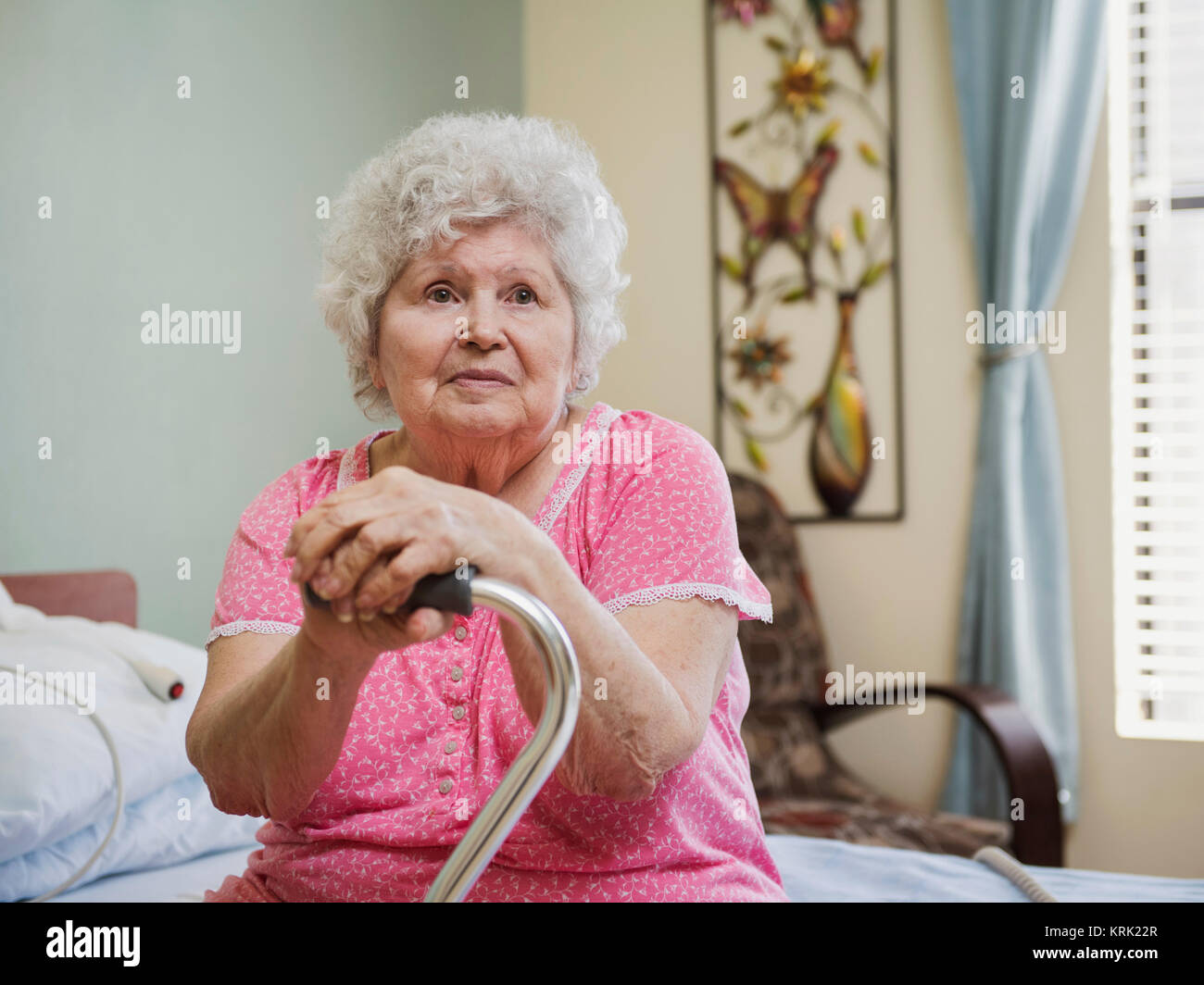 Grave Caucasian donna seduta sul letto appoggiato su di canna da zucchero Foto Stock