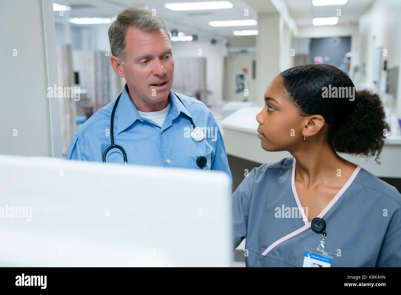 Medico e infermiere parlando vicino al computer Foto Stock
