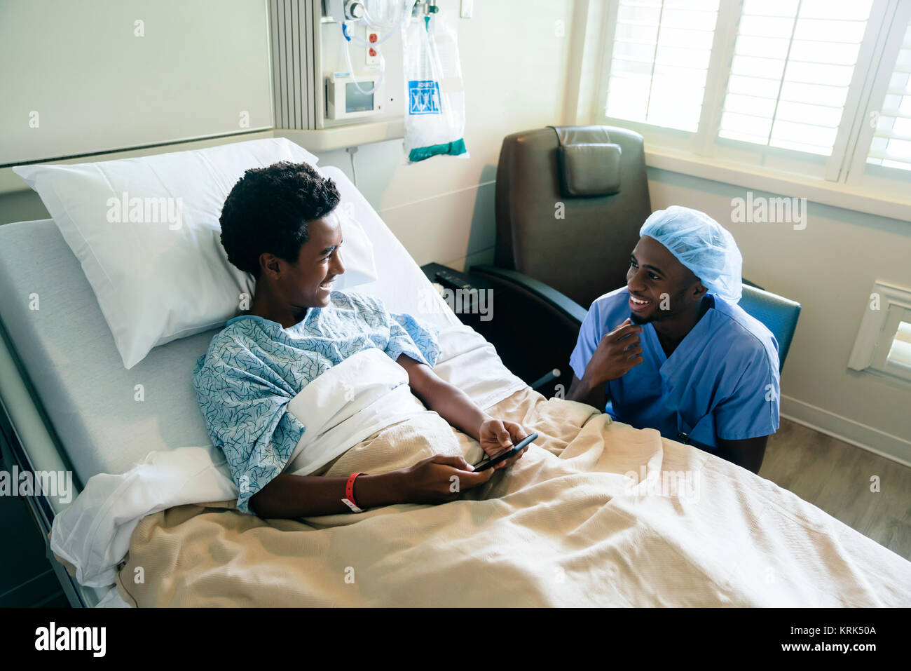 Infermiera nero parlando con il ragazzo nel letto di ospedale Foto Stock