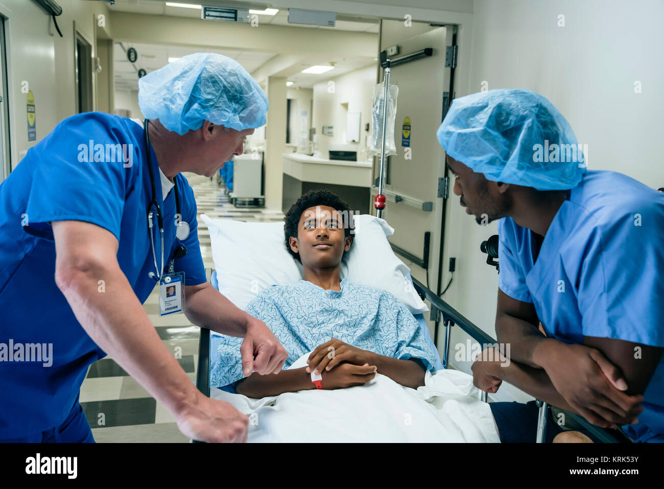 Gli infermieri parlando con il ragazzo in ospedale gurney Foto Stock