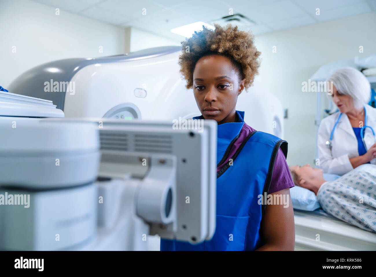 Il tecnico prepara scanner per medico paziente confortante Foto Stock