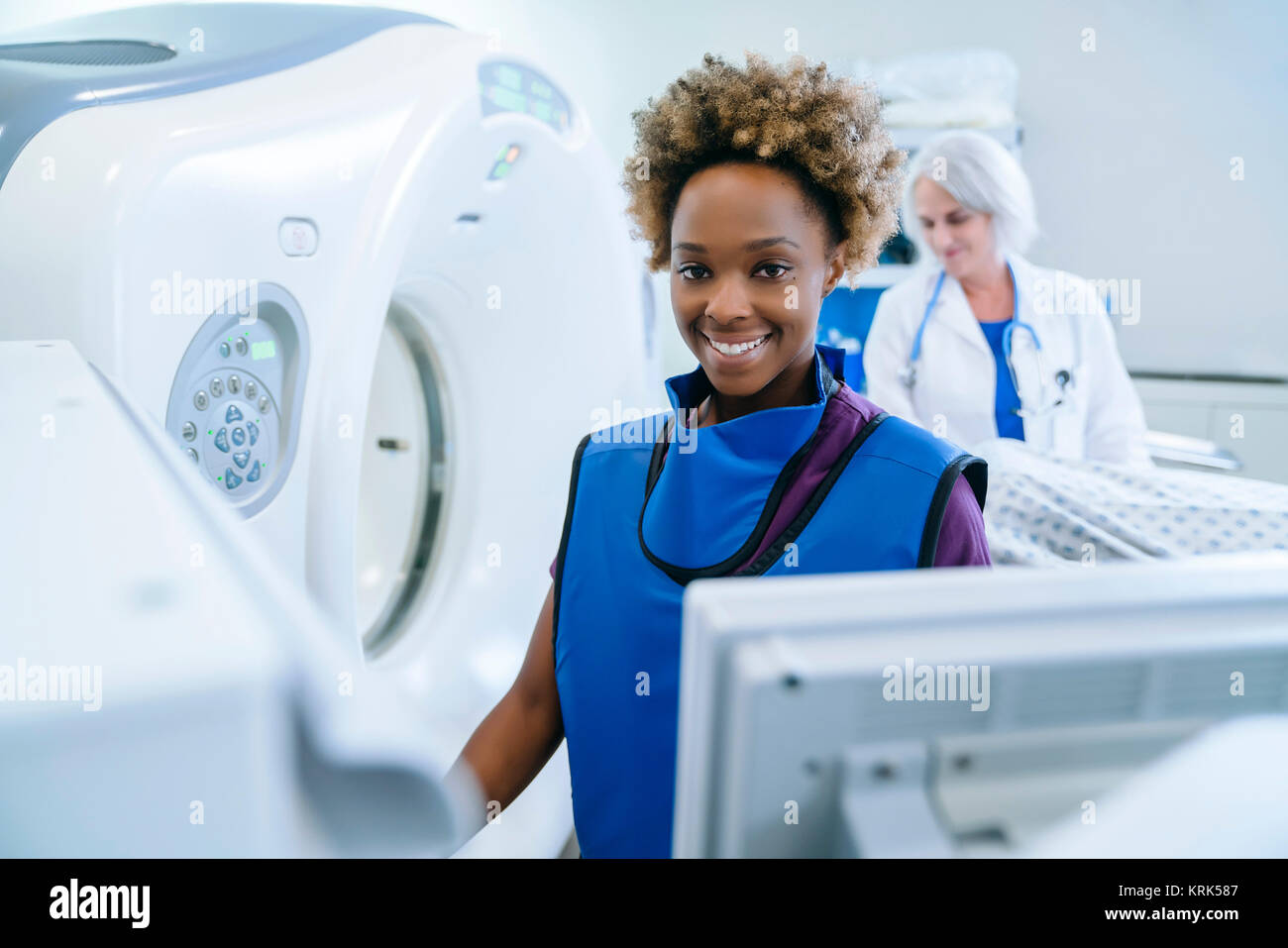Sorridendo il tecnico prepara scanner per medico paziente confortante Foto Stock