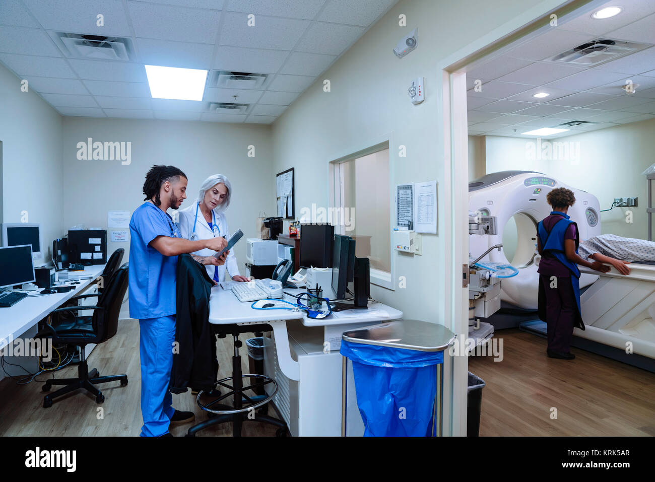 Medico e infermiere discutendo digitale compressa vicino a scanner Foto Stock
