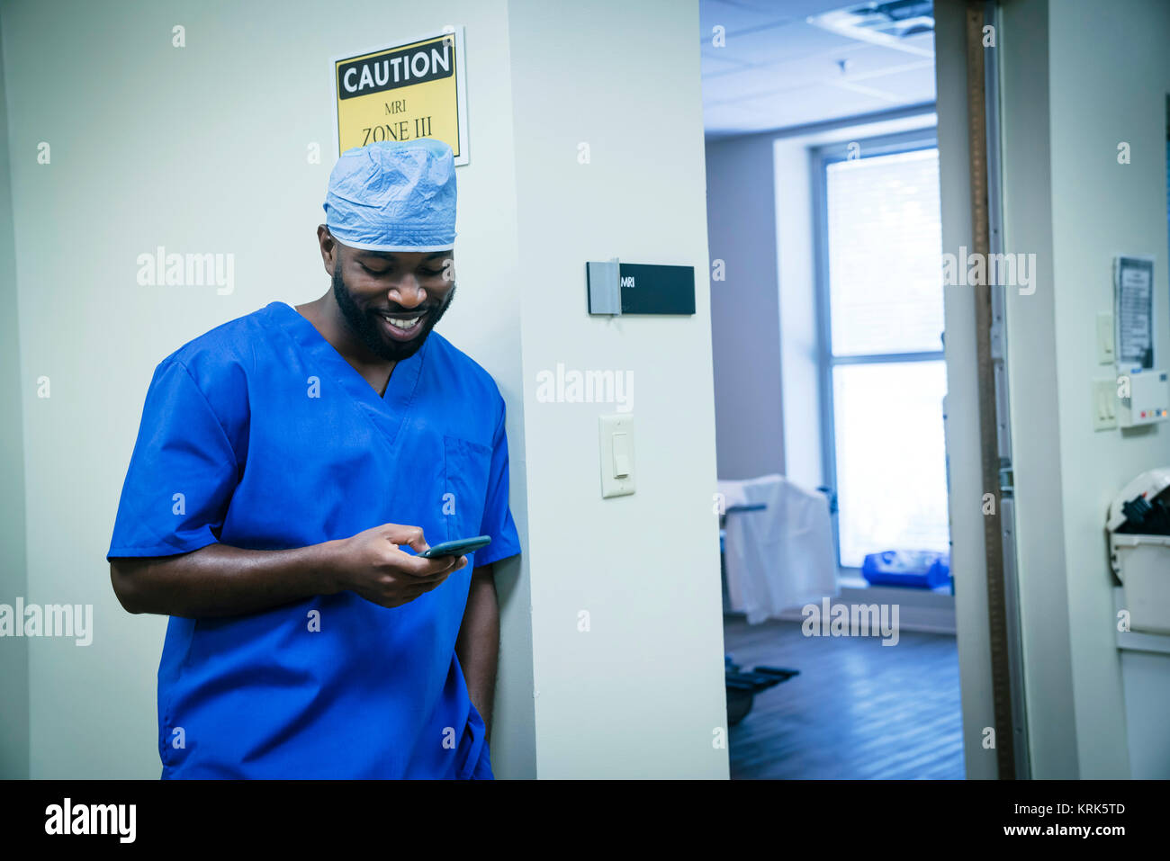 Sorridente infermiera nero scrivere messaggi su telefono cellulare Foto Stock