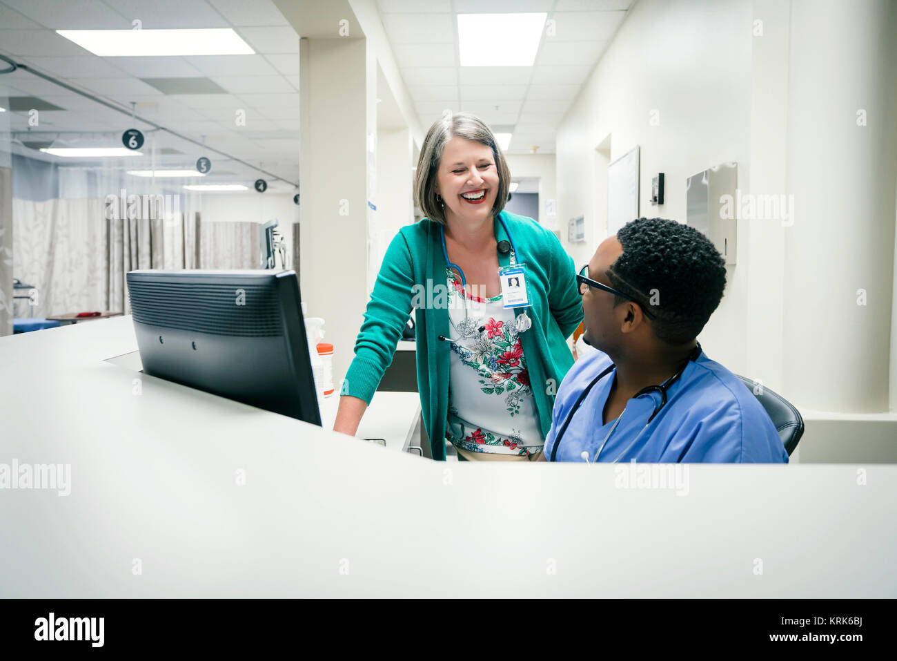 Medico e infermiere ridere vicino al computer Foto Stock
