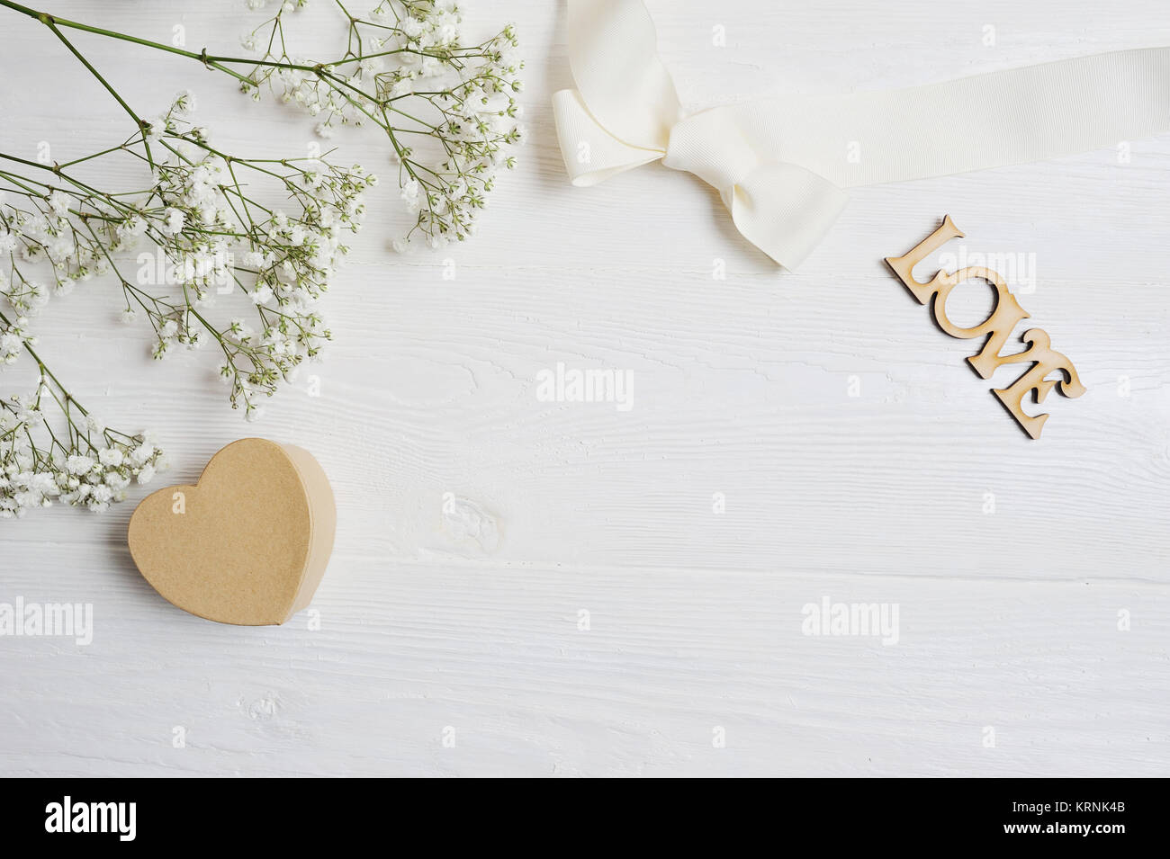 Mockup fiori composizione da un regalo bianca gypsophila con un cuore e un'iscrizione amore in bianco sullo sfondo di legno. Il giorno di San Valentino. Piatto, laici per Foto Stock