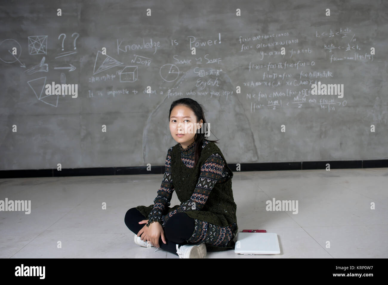 Studente asiatica in un classroomb studiando. Lo sfondo della lavagna. Foto Stock