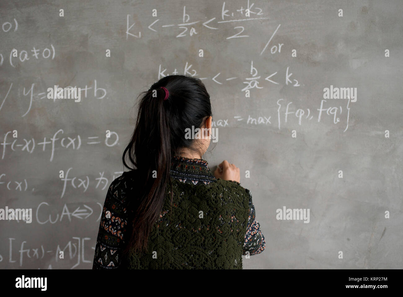 Gli asiatici collegio femminile studente che scrive sulla lavagna Lavagna durante una chimica classe Foto Stock