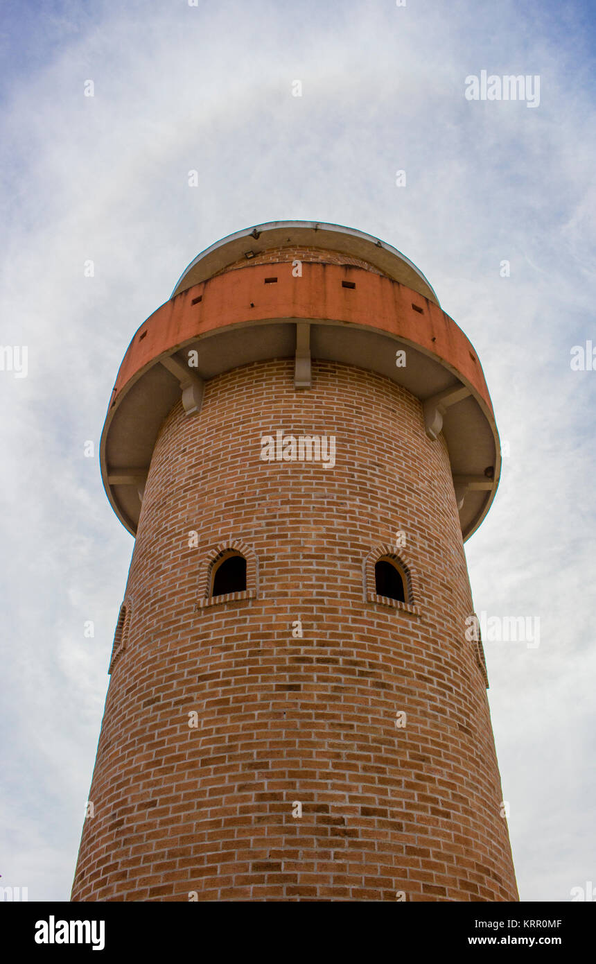 Chiusura del vecchio faro con cielo blu e bianca nuvola. Faro dal rosso mattone. Foto Stock