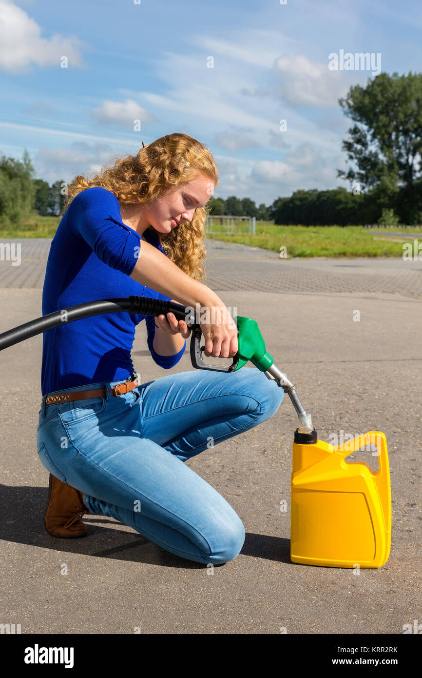 Giovane donna olandese di riempimento può essere di colore giallo con tubi flessibili per benzina all'aperto Foto Stock