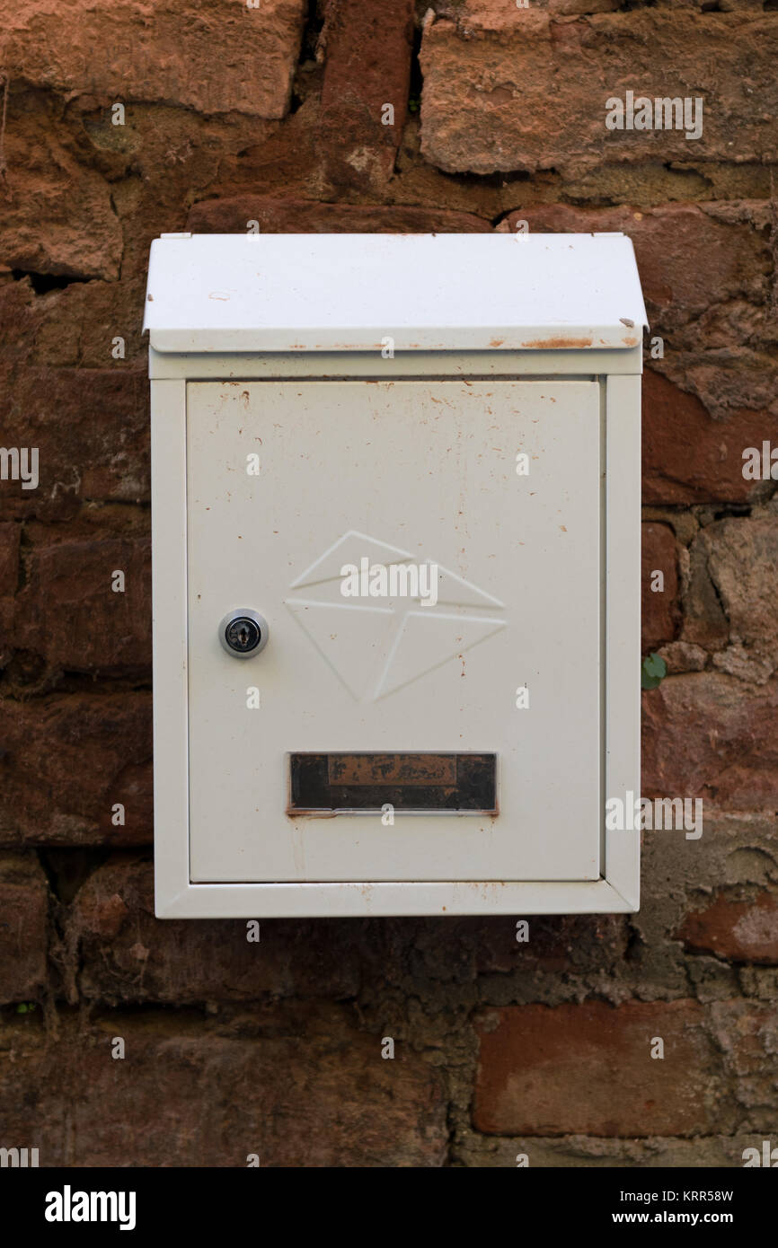 Metallo bianco sulla cassetta postale in rosso di un muro di mattoni. Il vecchio muro di mattoni. Mailbox coperto di polvere e di sporco. Foto Stock