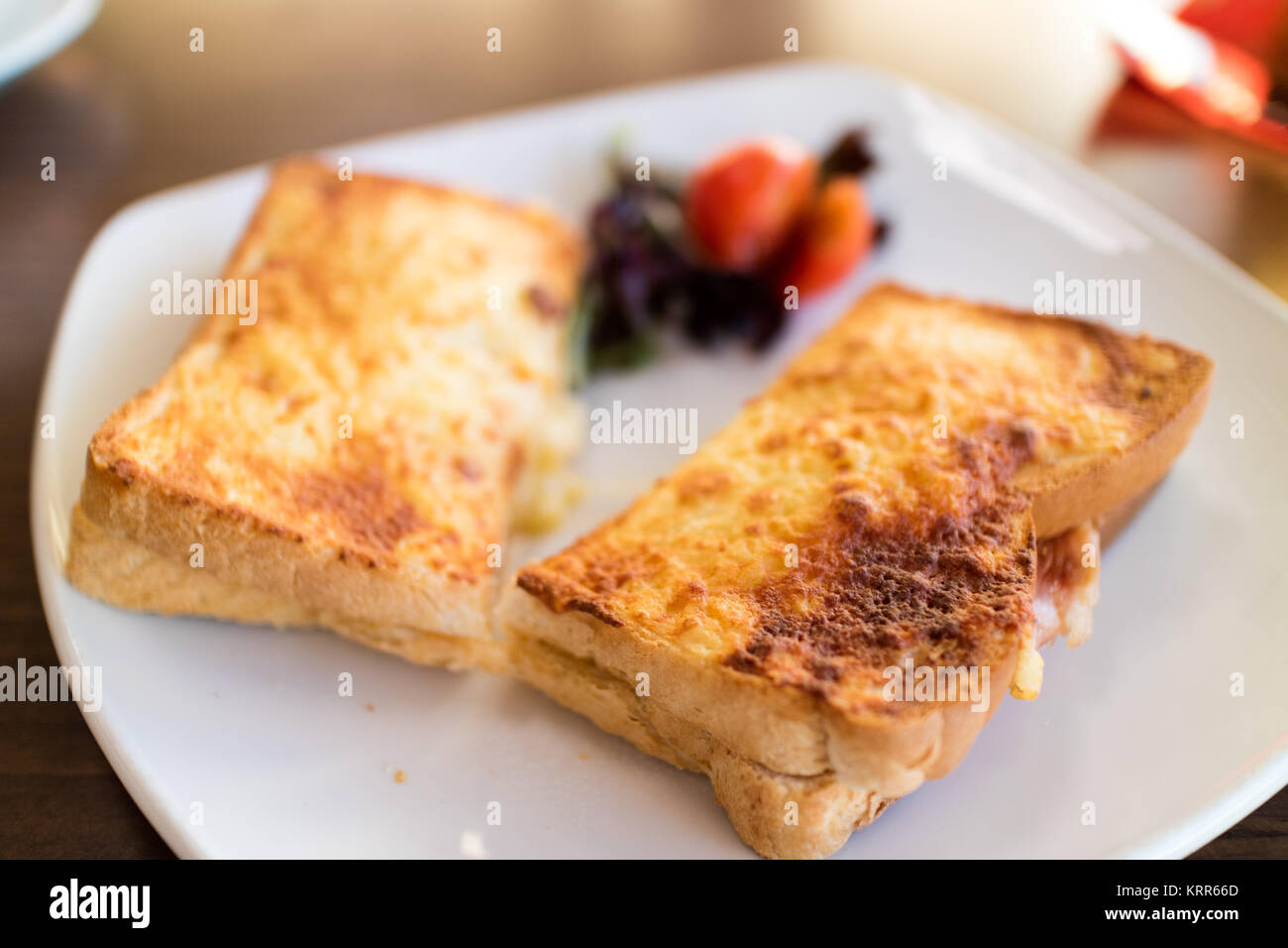 Un formaggio e pancetta toastie su una piastra bianca con contorno di insalata Foto Stock