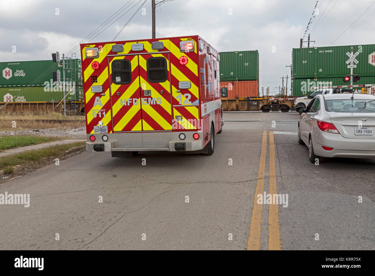 Houston, Texas - a Houston Vigili del Fuoco ambulanza EMS attende una lengthly treno merci per cancellare Quitman Street sul vicino lato nord. Foto Stock