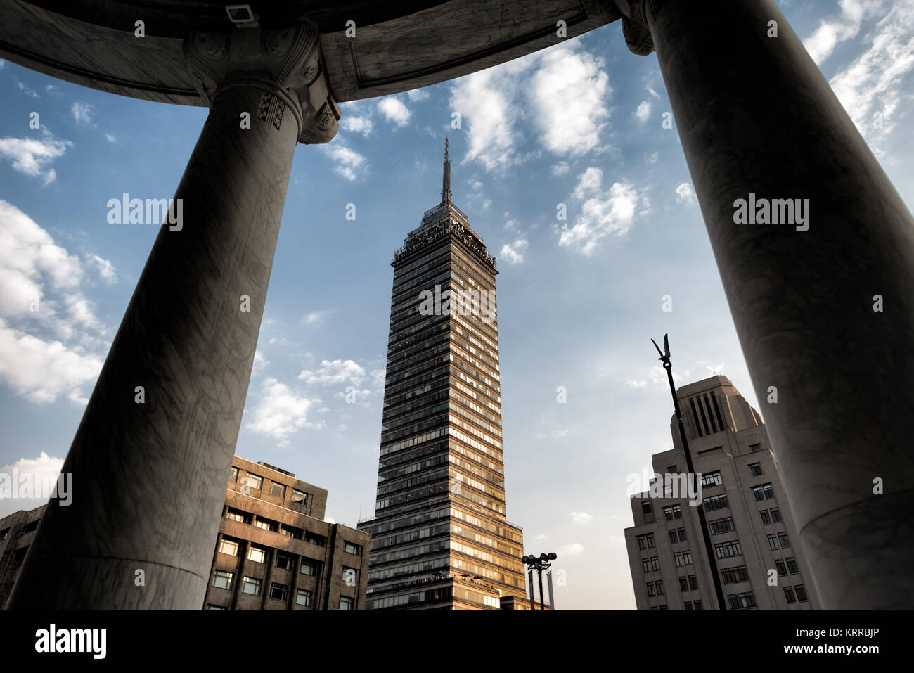 CITTÀ DEL MESSICO, Messico — Torre Latinoamericana cattura la luce del pomeriggio come si vede dalle colonne all'ingresso del Palacio de Bellas Artes. L'edificio sovrasta il quartiere Centro Historico di Città del Messico ed è uno dei principali punti di riferimento della zona. Fu il primo grattacielo maggiore costruito nell'area conosciuta per l'alta attività sismica. Foto Stock