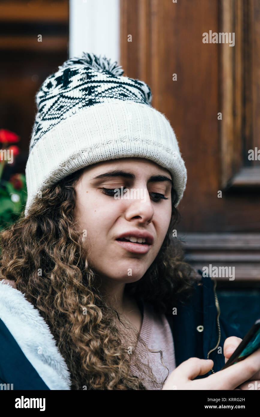 Ragazza adolescente in knit hat con strana espressione facciale texting wi Foto Stock