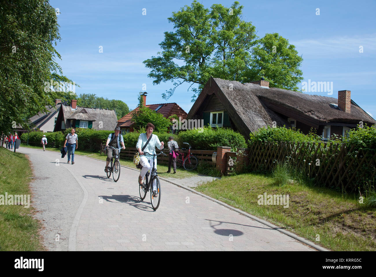 I ciclisti passando case col tetto di paglia al villaggio Kloster, isola di Hiddensee, Meclemburgo-Pomerania, Mar Baltico, Germania, Europa Foto Stock