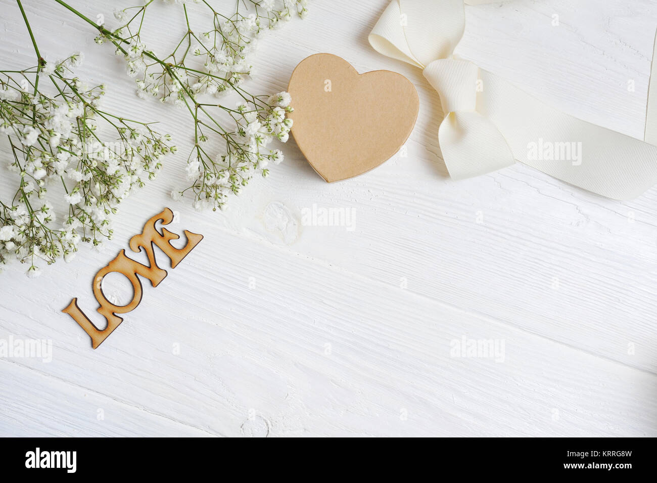 Mockup fiori composizione da un regalo bianca gypsophila con un cuore e un'iscrizione amore in bianco sullo sfondo di legno. Il giorno di San Valentino. Piatto, laici per Foto Stock