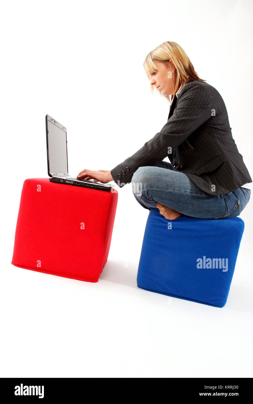 Junge Geschaeftsfrau sitzt auf Stoffwuerfel und arbeitet am Laptop - donna d'affari con computer portatile Foto Stock