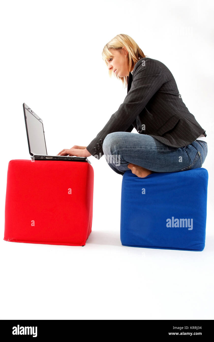 Junge Geschaeftsfrau sitzt auf Stoffwuerfel und arbeitet am Laptop - donna d'affari con computer portatile Foto Stock