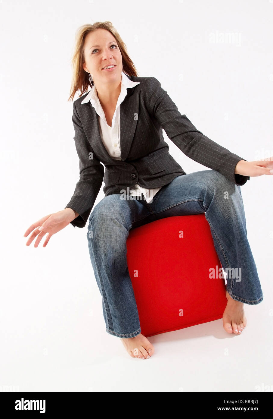 Blonde Frau, 25+, sitzt auf einem roten Stoffwuerfel - giovani, donna bionda in verticale Foto Stock