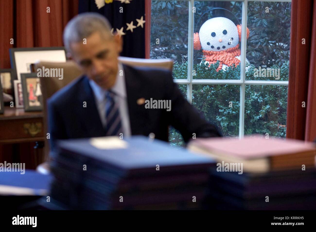 Un pupazzo di neve coetanei attraverso la finestra come Stati Uniti Il presidente Barack Obama lavora presso la risoluta scrivania in ufficio Ovale della Casa Bianca 16 Dicembre 2016 a Washington, DC. Foto Stock