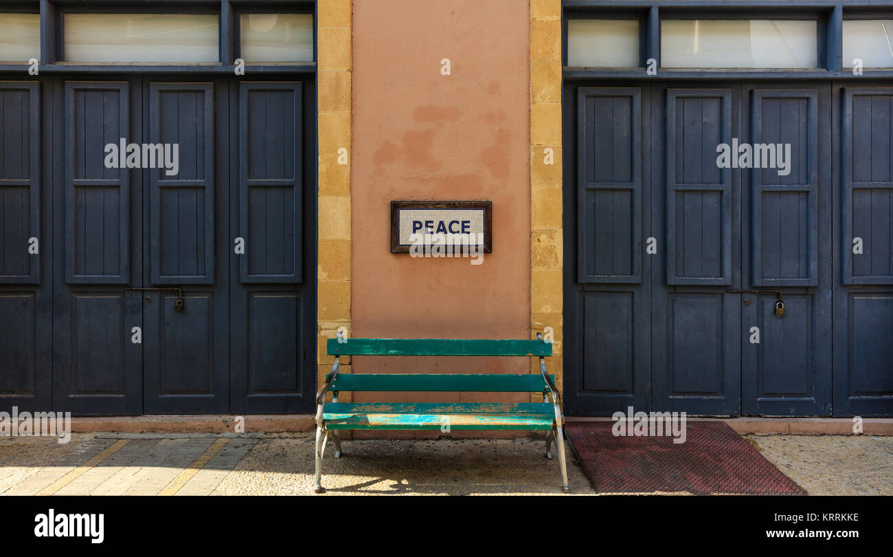 La parola pace incorniciata sopra un vecchio banco di legno su una colonna tra due porte chiuse. Vista ravvicinata. Foto Stock