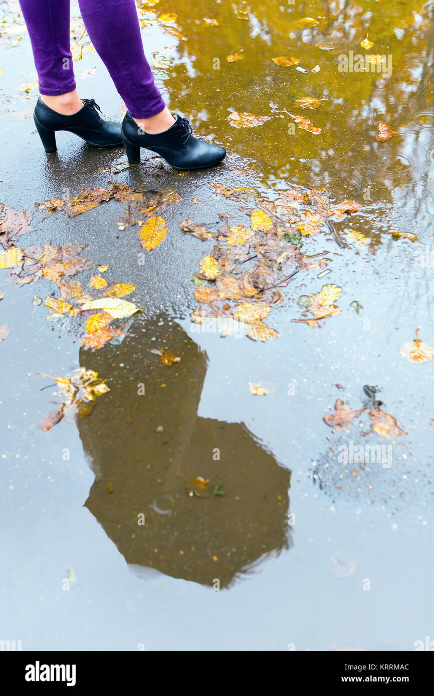 In caso di pioggia. Un uomo con un ombrello è riflessa in una pozzanghera. Foto Stock