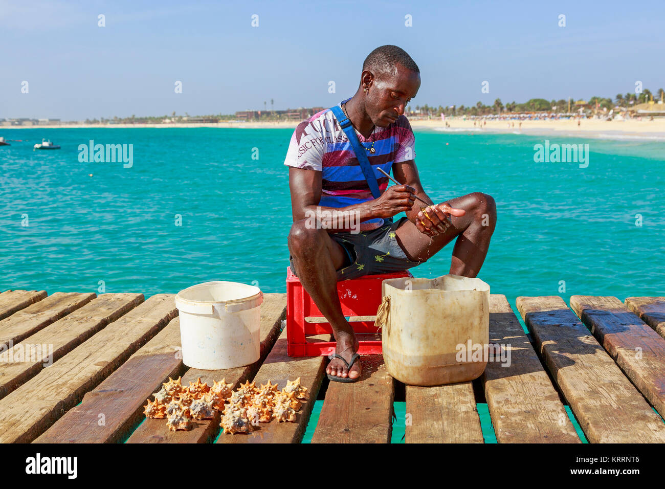 I pescatori locali seduti sul molo di Santa Maria, Sal, Salina, Capo Verde, Africa pulizia recentemente catturati conch gusci a vendere il negozio di souvenir Foto Stock