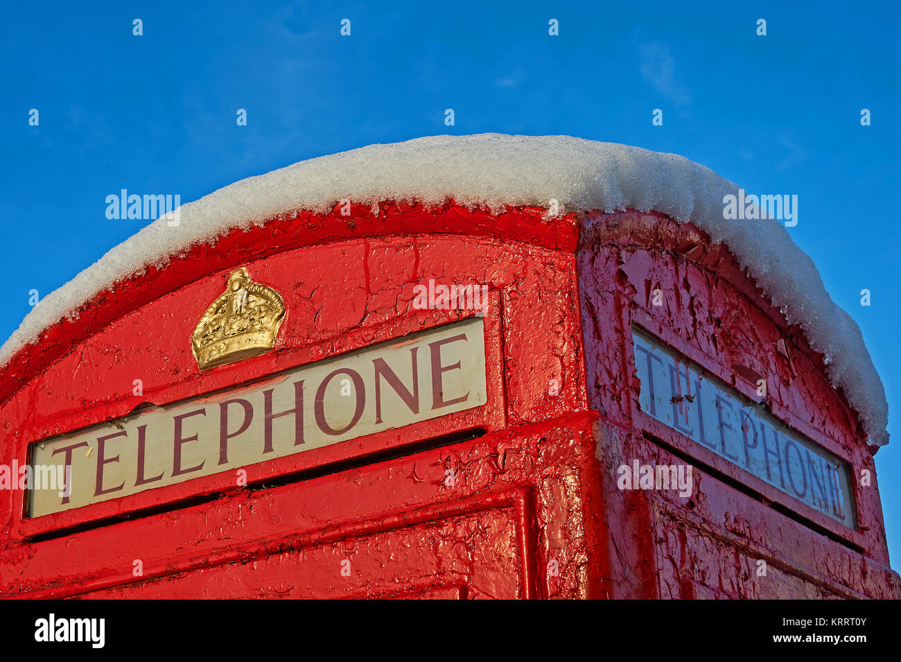 Iconico telefono rosso scatola contro un cielo blu, con un coperchio superiore di neve fresca Foto Stock