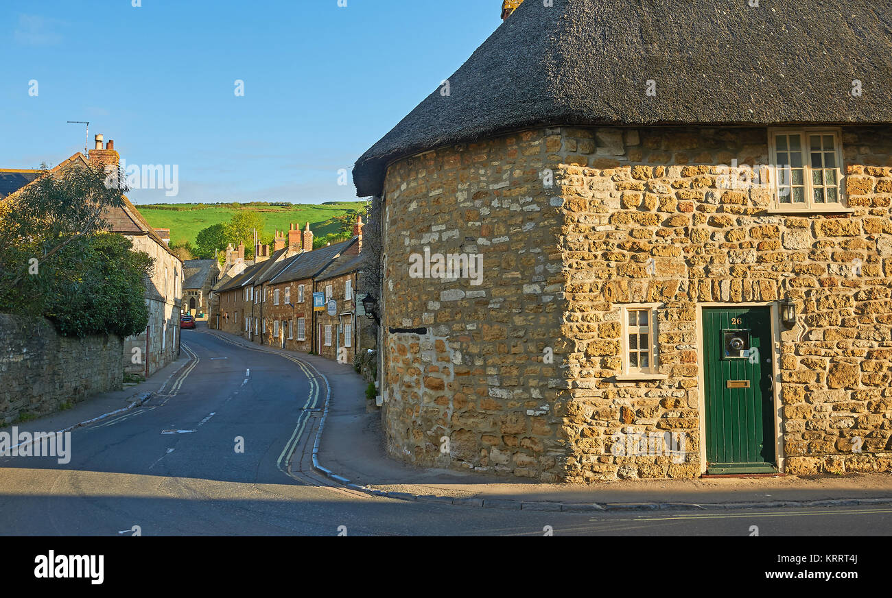 Streetscene nella graziosa Dorset villaggio di Abbotsbury, con cottage con il tetto di paglia sotto un cielo blu. Foto Stock