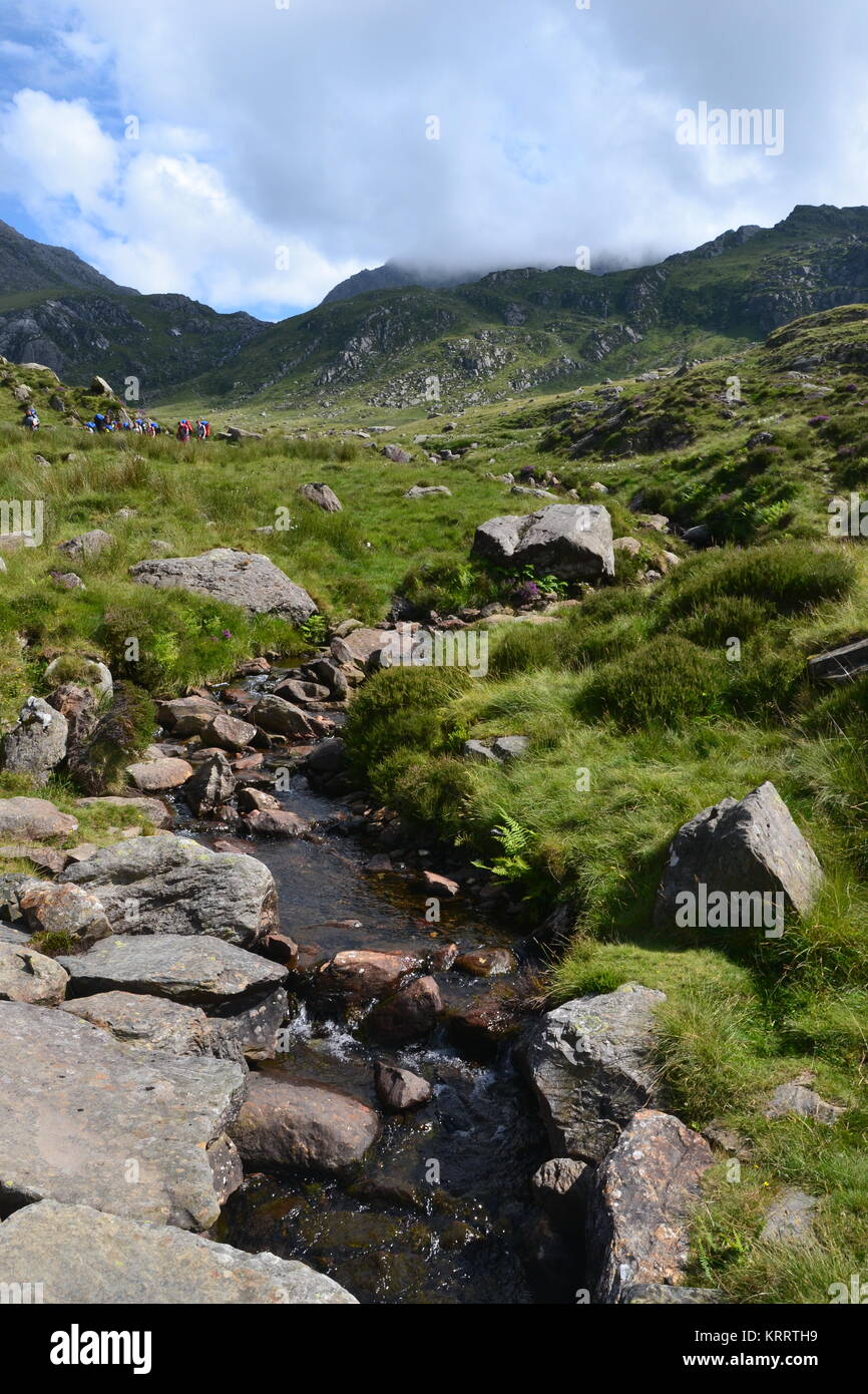 Gruppo di escursionisti sul monte Tryfan a piedi in direzione di Llyn Ogwen Foto Stock