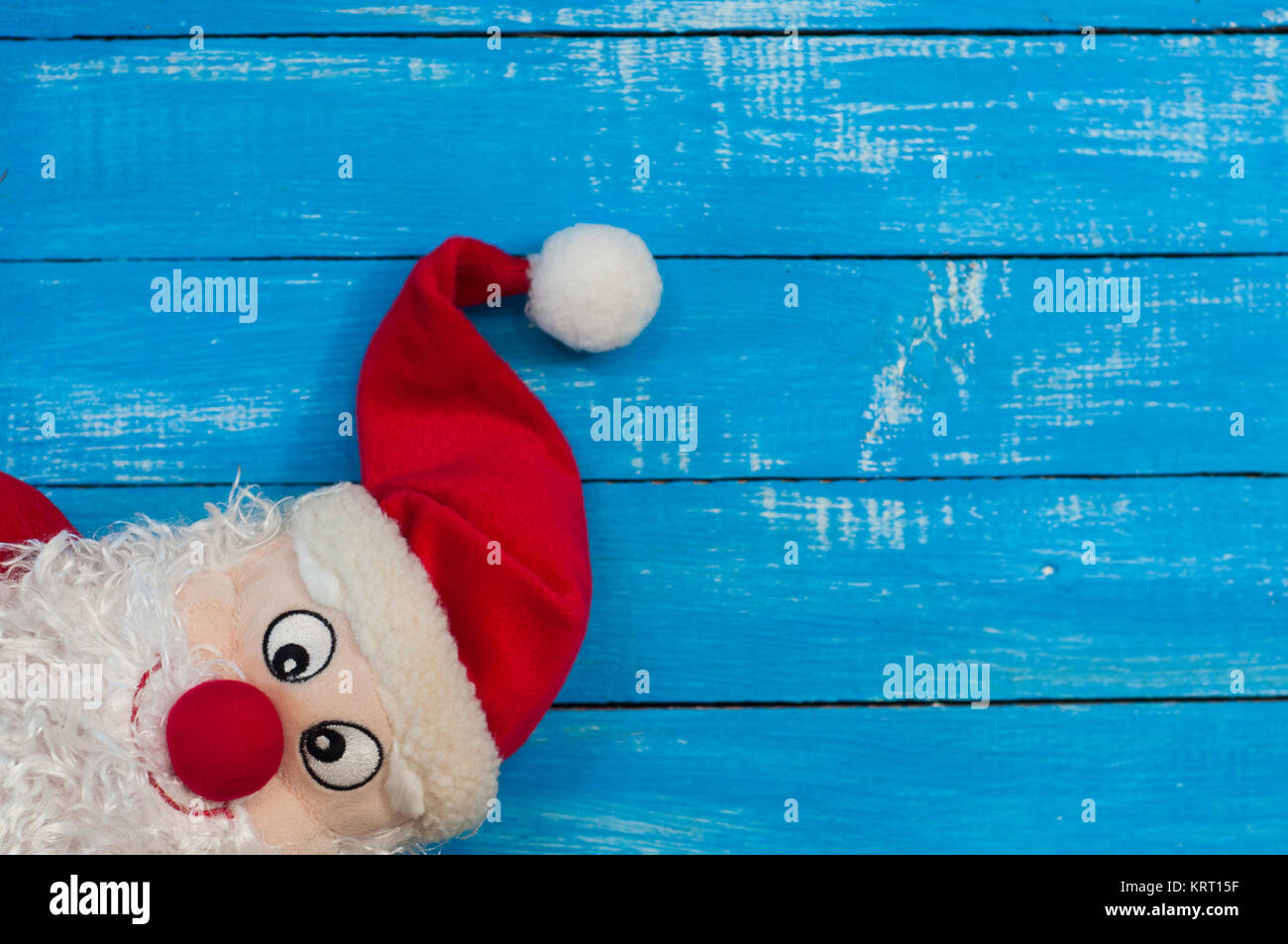 Sorridente Christmas Santa Claus in un cappuccio rosso blu sulla superficie di legno, lo spazio vuoto sulla destra Foto Stock