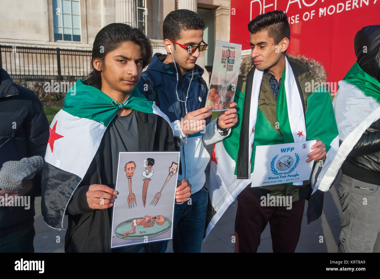 Manifestanti drappeggiati in libera Siria bandiere tenere poster a 'Cibo non bombe' per la Siria protesta in Trafalgar Square. Foto Stock