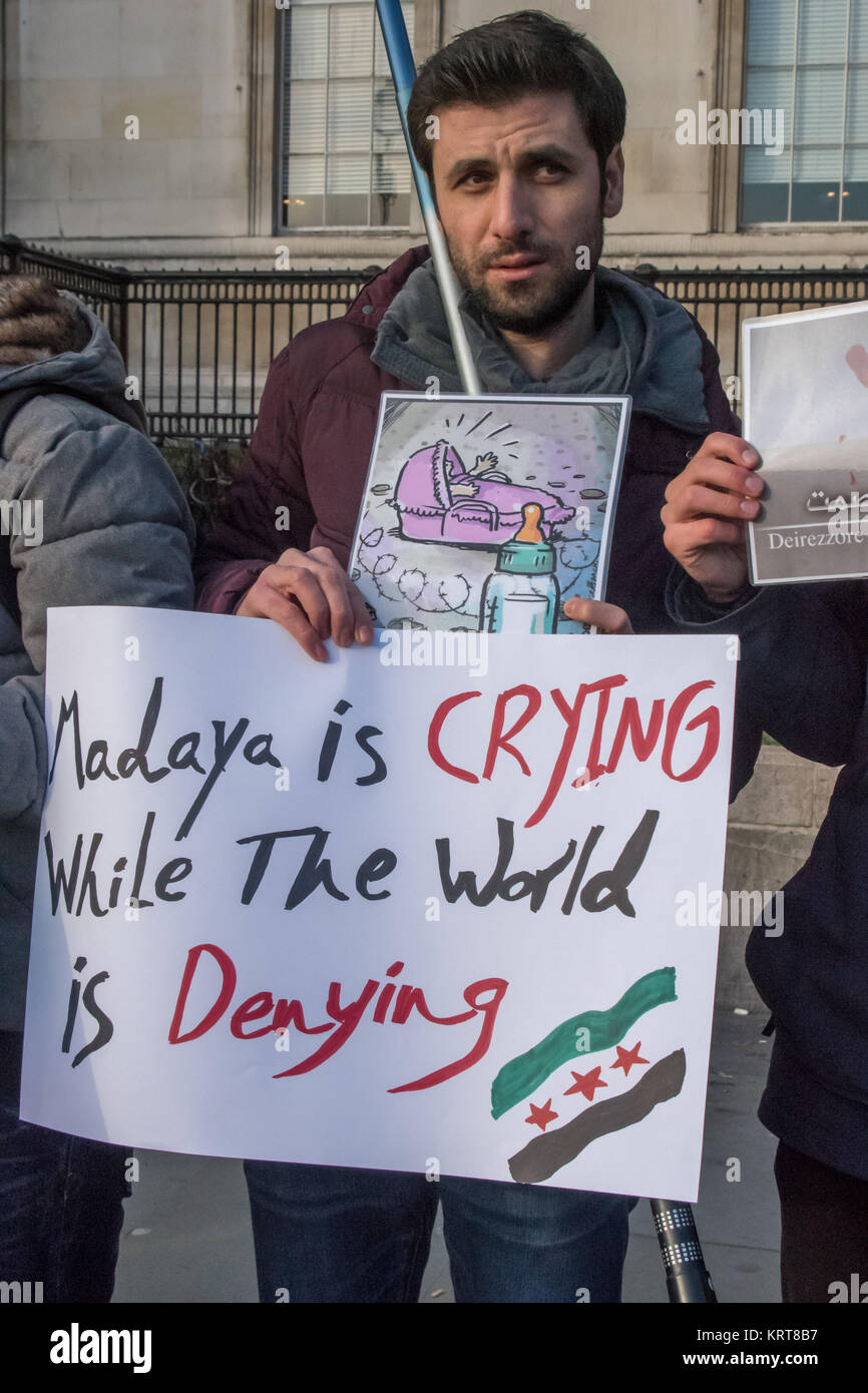 Un uomo detiene un poster 'Malaya è il pianto mentre il mondo è negare l' a 'siriana non alimentare le bombe" protesta in Trafalgar Square. Foto Stock