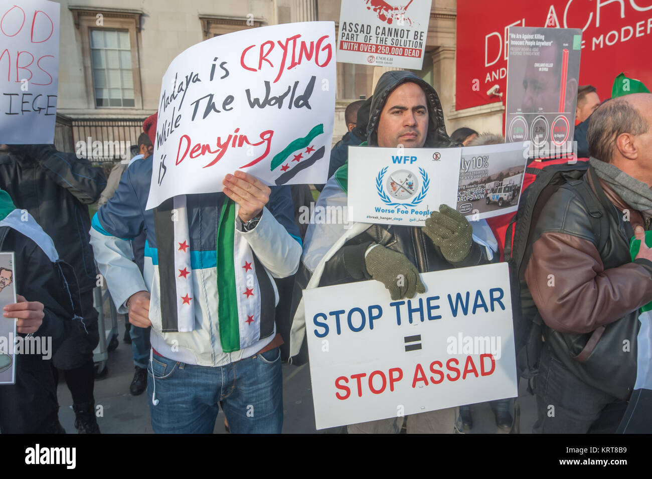 Gli uomini in attesa di poster a 'Cibo non bombe' per la Siria protesta in Trafalgar Square. Una legge 'Stop la guerra = Arresto Assad". Foto Stock